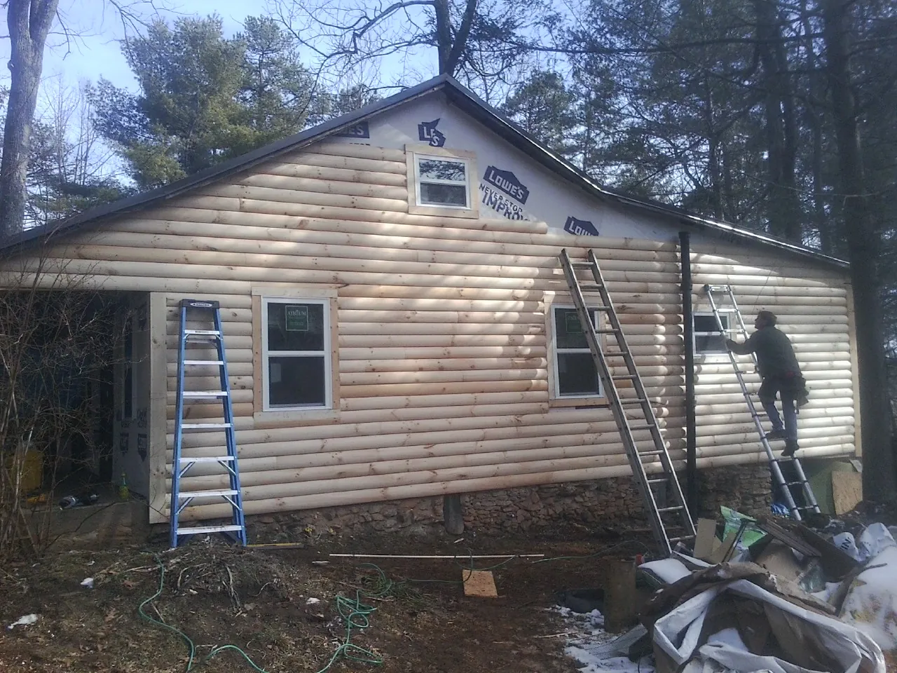 Ladders set against fresh log siding during an exterior remodel in Sergeant Bluff