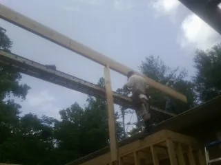 Carpenter setting a ridge beam over a new addition frame — Ice Dam Removal by Roofing Brothers in Sergeant Bluff