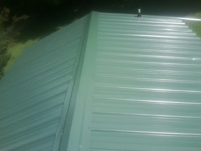 New green metal panels meeting at the ridge of a roof — Flat Roof Repair work by our crew in Sergeant Bluff
