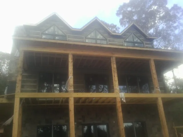 Dormers and porch framing on a large log home under construction — Roof Coating work by our crew in Sergeant Bluff